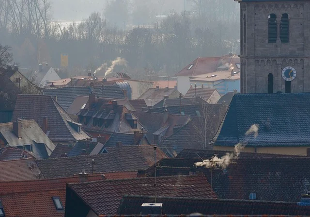 Dym z kominów nad dachami domów w chłodny jesienny poranek